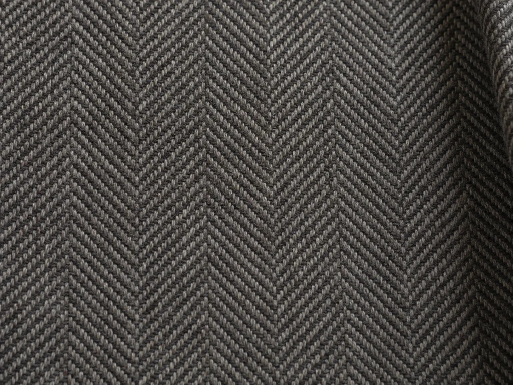 Close-up of charcoal grey herringbone wool-blend fabric showing the distinctive broken zigzag weave.