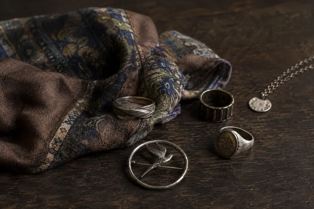 Mismatched rings and an old brooch beside a patterned silk scarf
