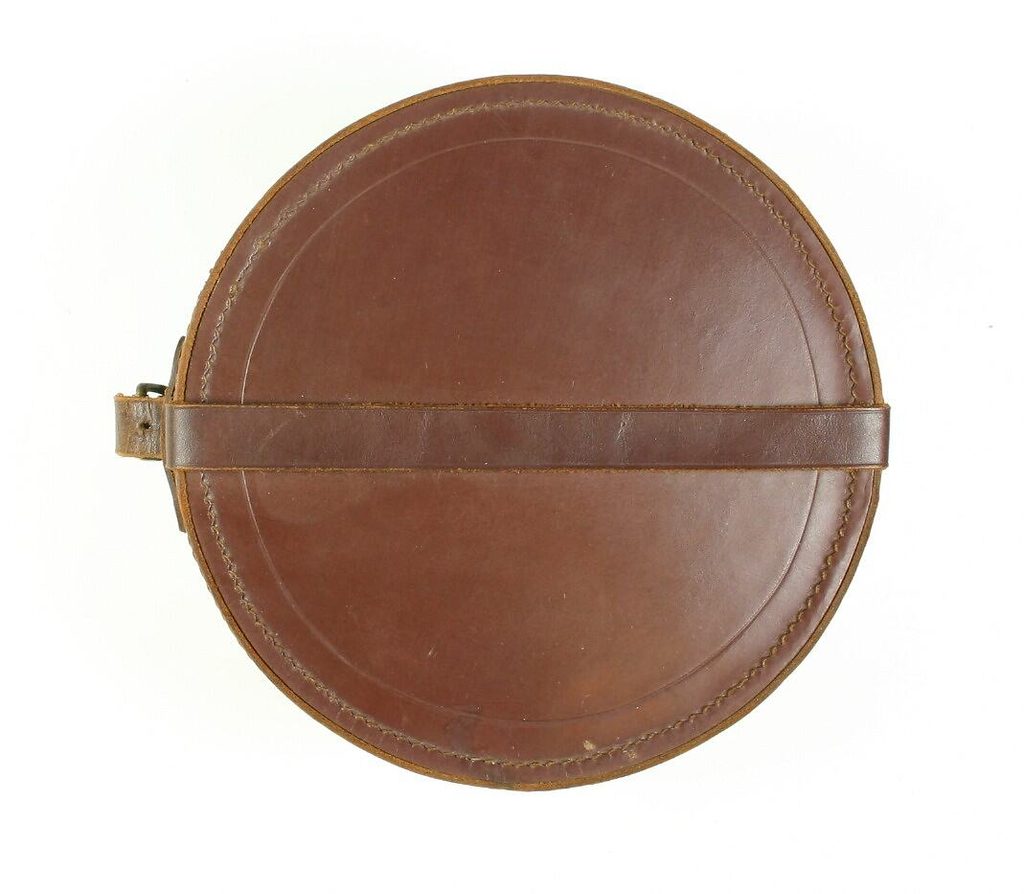 Round brown leather collar box containing several stiff white detachable shirt collars.