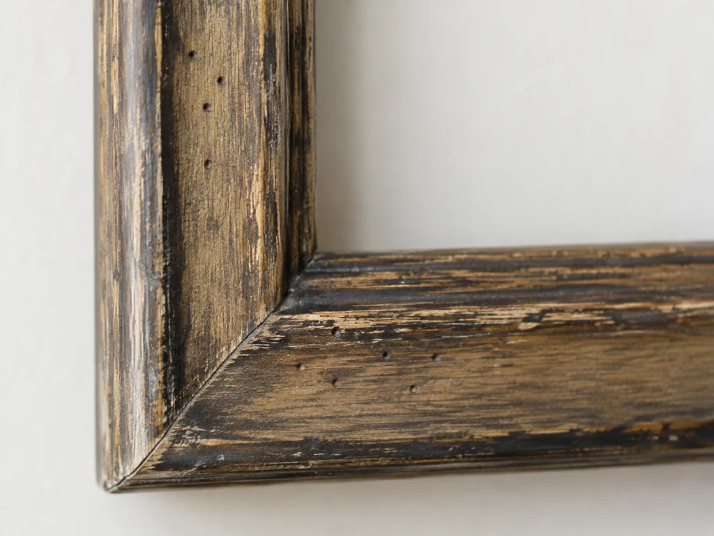 Deliberately distressed wooden picture frame with decorative fake worm holes.