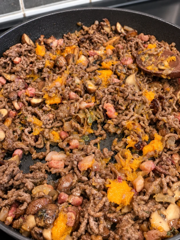 Beef, pancetta and chestnut mushroom filling with roasted butternut squash folded through it in a frying pan.