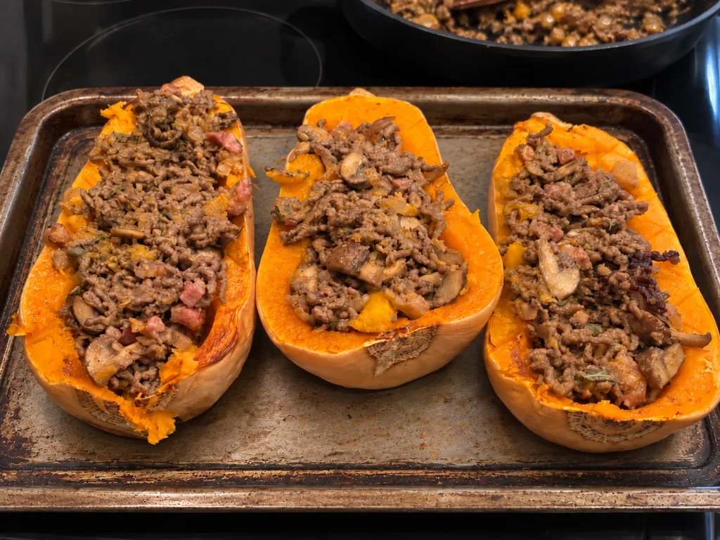 Three roasted butternut squash halves generously filled with beef, pancetta and mushroom mixture before the breadcrumb topping is added.