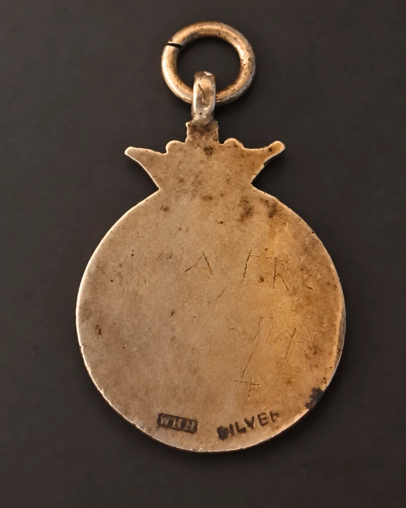 Back of a worn second-hand fob medal stamped SILVER beside a separate rectangular punch.